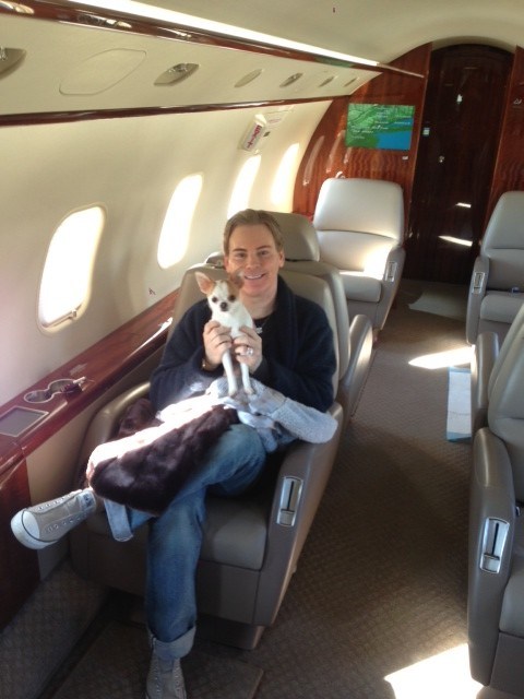 gorgeous celebrity Jerrod Blandino holding a fawn and white chihuahua puppy in a private plane